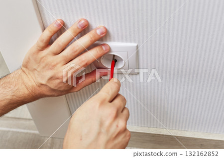electrician installing electrical wall socket with a screwdriver at home, close-up 132162852