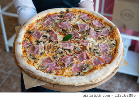 Homemade italian pizza in hand with ham and mushhrooms tasty big Homemade italian pizza in hand with ham and mushhrooms tasty big 132162896