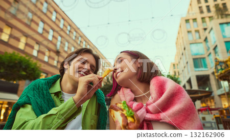 Young couple smiling and feeding each other fries in romantic city moment Young couple smiling and feeding each other fries in romantic city moment 132162906