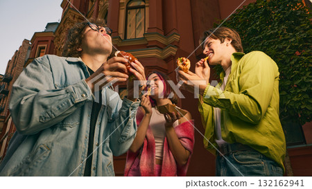 Group of young friends eating burgers and fries together on city street Group of young friends eating burgers and fries together on city street 132162941
