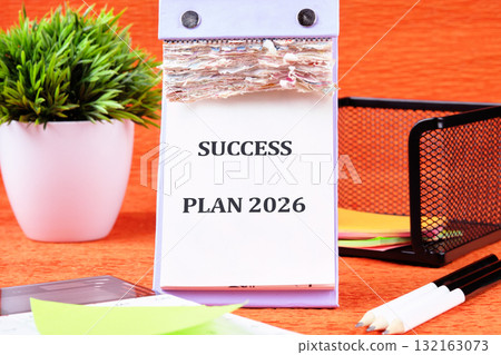 A neat workspace showcases a success plan for 2026, featuring a calendar, vibrant colors, and organized stationery, fostering motivation and focus on achieving goals 132163073