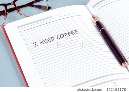 A cozy workspace features a notebook with the urgent plea for coffee written in bold letters. A stylish pen lies nearby, waiting for new ideas fueled by caffeine 132163178