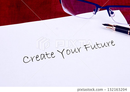 A handwritten note expresses hope and motivation, inviting personal growth. A pen rests beside glasses on a clean surface, suggesting contemplation and future planning 132163204