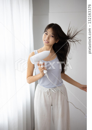 A young lady who dries her hair with a hair dryer A young lady who dries her hair with a hair dryer 132163376