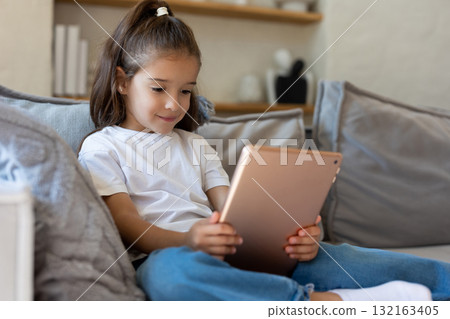 Female child playing with digital tablet in living room 132163405