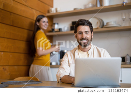 Bearded man working on his laptop in the kitchen 132163474