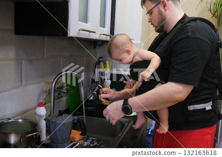 Father Washing Dishes with Baby in Carrier 132163618