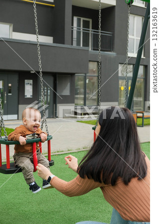 Mother and Baby on Swing in Playground Mother and Baby on Swing in Playground 132163619
