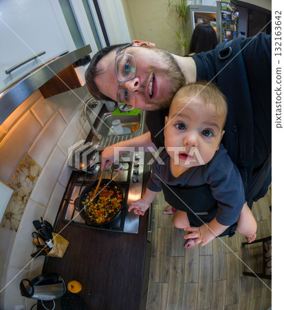 Father Cooking with Baby in Carrier 132163642