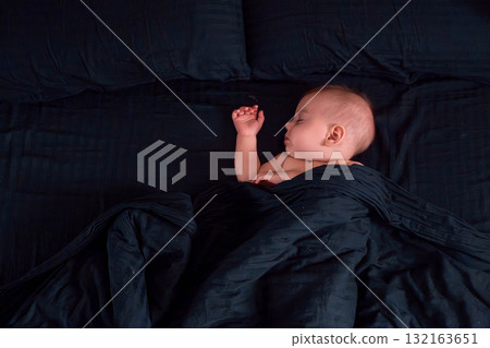 Peaceful baby sleeping on dark bedding 132163651
