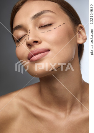 Woman with surgical markings and calm closed eyes symbolizing trust and transformation Woman with surgical markings and calm closed eyes symbolizing trust and transformation 132164689