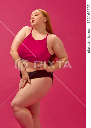 Plus-size model in pink top and black bottoms showing natural confidence and style Plus-size model in pink top and black bottoms showing natural confidence and style 132164705