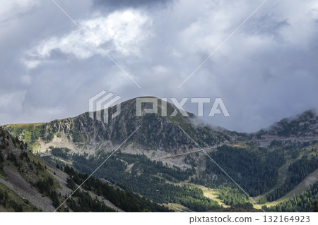 Alpine road winding through Piedmont mountains under clouds 132164923