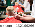 Barber using comb and shaver to cut hair. Professional hairdresser shaving little kid's nape. 132166266