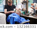 Hairdresser shaving boy's head. Competent barber using electric shaver at barbershop. Little client getting stylish men's haircut. 132166331