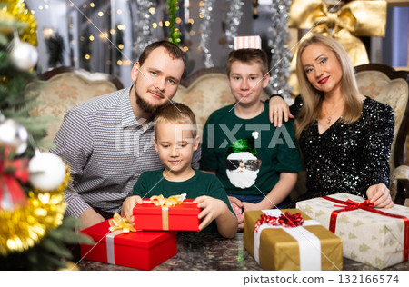 Smiling family celebrating Christmas and giving each other gifts 132166574