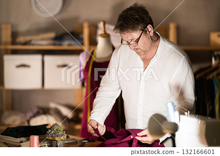 Middle-aged male dressmaker reviewing jeans to restore 132166601