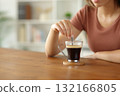 Woman hand is stirring coffee on a wooden table 132166805