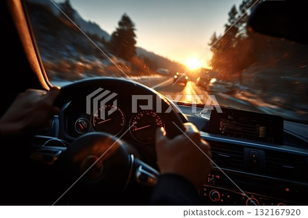 Driver holding steering wheel while driving on road at sunset Driver holding steering wheel while driving on road at sunset 132167920
