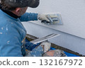Worker applying plaster to building wall with trowel 132167972
