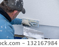 Worker plastering wall facade using hand trowel 132167984