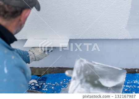 Worker plastering wall with stucco during renovation project 132167987