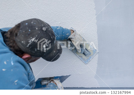 Worker plastering stucco on building exterior wall Worker plastering stucco on building exterior wall 132167994