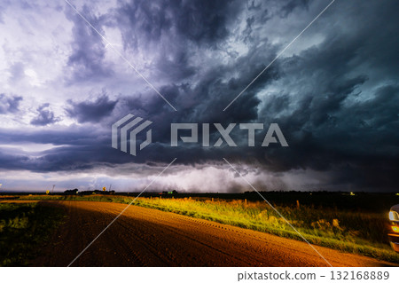 Bright lightning flashes in a dark storm cloud over country road Bright lightning flashes in a dark storm cloud over country road 132168889