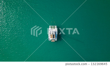 Top down drone view of white sailing catamaran anchored on turquoise lagoon minimal composition calm summer water 132169645