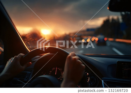 Driver holding steering wheel while driving on highway at sunset 132169720