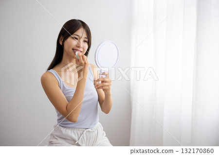 Young woman applying lip balm 132170860