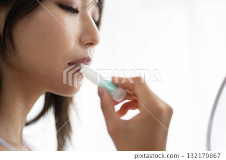 Young woman applying lip balm 132170867