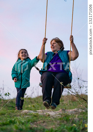 Grandmother and granddaughter sharing a joyful swing ride at sunset. Precious moment of intergenerational connection and playful fun. Grandmother and granddaughter sharing a joyful swing ride at sunset. Precious moment of intergenerational connection and playful fun. 132171006