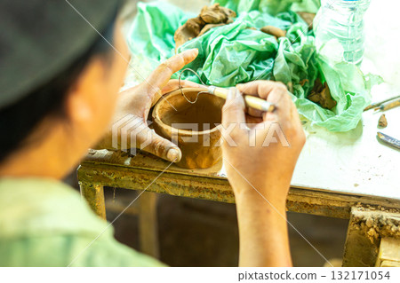 Hand shaping clay pottery in workshop 132171054