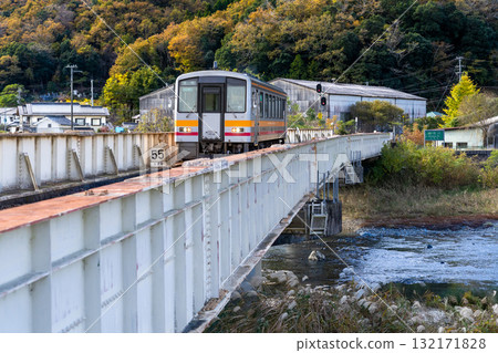 Late autumn on the Kishin Line: Local train 1 bound for Yoyo Station crossing the railway bridge over the Sayo River. Sayo Town, Sayo District, Hyogo Prefecture. Late autumn on the Kishin Line: Local train 1 bound for Yoyo Station crossing the railway bridge over the Sayo River. Sayo Town, Sayo District, Hyogo Prefecture. 132171828