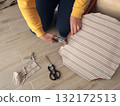 Anonymous person restore old vintage chair in home. Fabric replacement. Antique furniture and modern striped linen and cotton fabric. Hobbies, crafts, and retro-minimalist style. 132172513