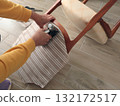 Anonymous person restore old vintage chair in home. Fabric replacement. Antique furniture and modern striped linen and cotton fabric. Hobbies, crafts, and retro-minimalist style. 132172517