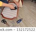 Anonymous person restore old vintage chair in home. Fabric replacement. Antique furniture and modern striped linen and cotton fabric. Hobbies, crafts, and retro-minimalist style. 132172522