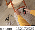 Anonymous person restore old vintage chair in home. Fabric replacement. Antique furniture and modern striped linen and cotton fabric. Hobbies, crafts, and retro-minimalist style. 132172525