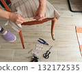 Anonymous person restore old vintage chair in home. Fabric replacement. Antique furniture and modern striped linen and cotton fabric. Hobbies, crafts, and retro-minimalist style. 132172535