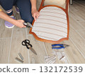 Anonymous person restore old vintage chair in home. Fabric replacement. Antique furniture and modern striped linen and cotton fabric. Hobbies, crafts, and retro-minimalist style. 132172539