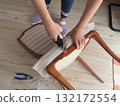 Anonymous person restore old vintage chair in home. Fabric replacement. Antique furniture and modern striped linen and cotton fabric. Hobbies, crafts, and retro-minimalist style. 132172554