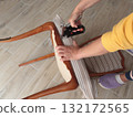 Anonymous person restore old vintage chair in home. Fabric replacement. Antique furniture and modern striped linen and cotton fabric. Hobbies, crafts, and retro-minimalist style. 132172565