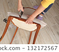 Anonymous person restore old vintage chair in home. Fabric replacement. Antique furniture and modern striped linen and cotton fabric. Hobbies, crafts, and retro-minimalist style. 132172567