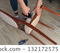 Anonymous person restore old vintage chair in home. Fabric replacement. Antique furniture and modern striped linen and cotton fabric. Hobbies, crafts, and retro-minimalist style. 132172575