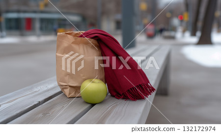 Green apple with paper bag and red scarf on a wooden bench in a winter city park Green apple with paper bag and red scarf on a wooden bench in a winter city park 132172974