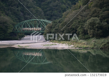 河面上倒映的鐵路橋和當地火車 河面上倒映的鐵路橋和當地火車 132173819