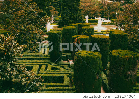 Formal garden with trimmed hedges and statues. A beautiful formal garden features meticulously trimmed hedges, pathways, and elegant statues, creating a serene and picturesque landscape. Formal garden with trimmed hedges and statues. A beautiful formal garden features meticulously trimmed hedges, pathways, and elegant statues, creating a serene and picturesque landscape. 132174064