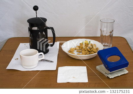 Still life with a coffee press and a hole punch. Still life with a coffee press and a hole punch. 132175231
