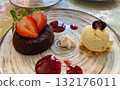 A delicious and beautifully plated gourmet dessert featuring a rich chocolate lava cake, or fondant, topped with fresh sliced strawberries 132176011